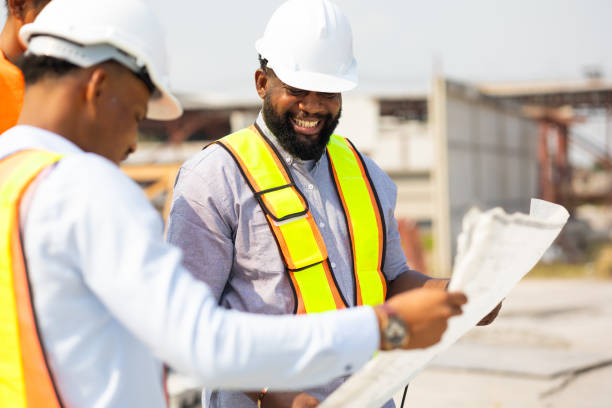 istock Happy Engineering worker in safety hardhat and architect looking at blueprint at industrial Heavy Manufacturing Factory. Prefabricated concrete walls. Professional Engineer Team working 1560514343