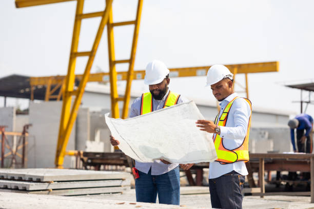 Professional Engineer Team working. Engineering worker in safety hardhat and architect looking at blueprint at factory industrial facilities. Heavy Industry Manufacturing Factory. Prefabricated concrete walls equipo de ingeniero profesional trabajando. trabajador de ingeniería en casco de seguridad y arquitecto mirando el plano en las instalaciones industriales de la fábrica. fábrica de fabricación de la industria pesada. muros prefabricados de hormigón