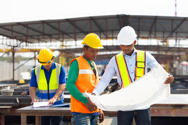 istock Professional Engineer Team working. Young architect Engineering and asian worker in safety hardhat and  looking at blueprint at industrial Heavy Manufacturing Factory. Prefabricated concrete walls 1560515395