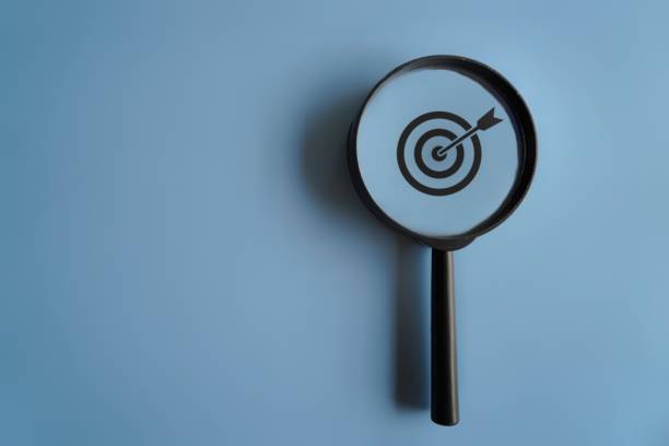 istock Target board and magnifying glass with copy space on blue background. 1560518630