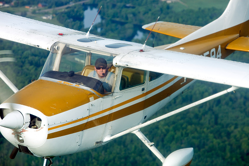 A classic airplane is flying over a wooded area with a lake in the background. Shot from another airplane at a close distance.\u2028http://www.banksphotos.com/LightboxBanners/Aircraft.jpg