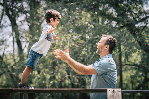 istock Father with his son having fun outside in forest jump arm 1560527294