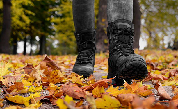 Woman Hiking In The Woods Low perspective, front view. Woman wearing black boots. Autumn walking in yellow and orange leaves. hott stock pictures, royalty-free photos & images