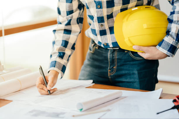 istock The concept of construction of an architect or engineer. Holding a pen planning a project design on a blueprint in hand holding a yellow helmet in the workplace He was wearing a formal suit. 1560553064