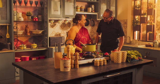 istock Indian Couple Exploring Traditional Cooking: Preserving Culinary Heritage, Preparing Authentic Recipes with Love and Care. Laughing and Having Fun in the Kitchen, Bright Sunny Festive Day. Medium Shot 1560592128