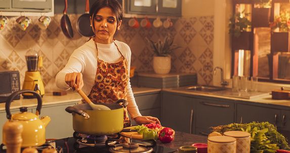 Indian Girl Preparing Food: Magnificent Young Woman Preparing Delicious Home-Cooked Traditional Meal. Celebrating Traditional Culture in Cosy Kitchen. Housewife Trying a New Recipe for her Family