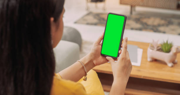 Over the Shoulder Indian Girl Using Smartphone with Green Green Screen Screen: Browsing Social Media, Staying Connected with Friends, Doing Online Shopping, Close-up .