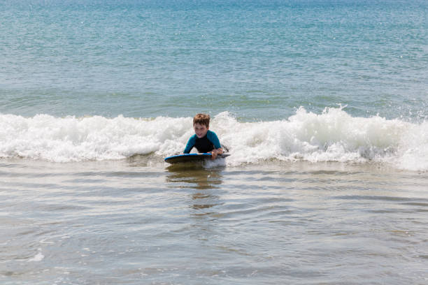Young boy boogie boarding on a wave. stock photo
