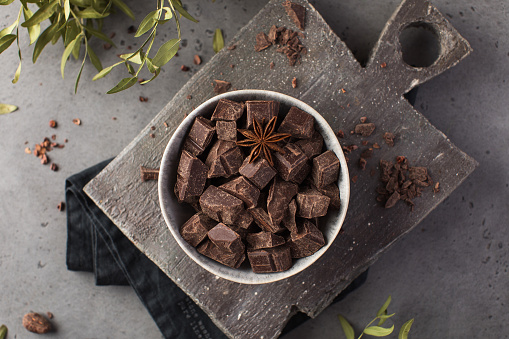 Cubes of dark artisan chocolate on a grey background. Organic bitter chocolate.