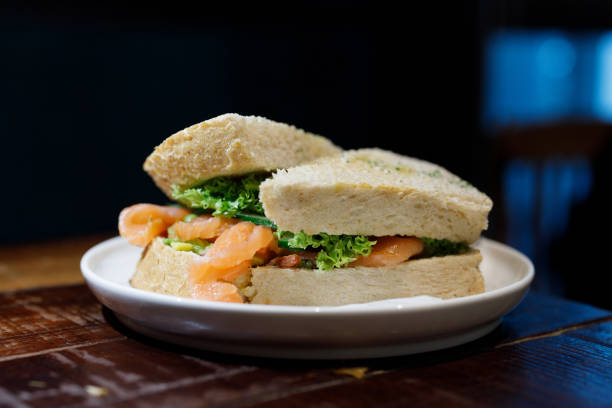 Toasted bread with avocado spread, salmon and lettuce served on a white plate