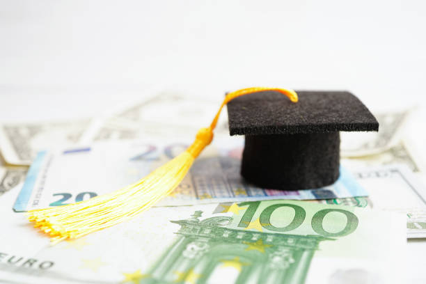 istock Graduation gap hat on US dollar banknotes money, Education study fee learning teach concept. 1560657320