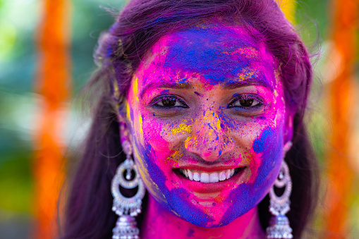 Head shot of young indian girl with holi color applied on face during holi festival celebration - concept of indian culture, ceremony and happiness.
