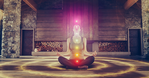Beautiful Relaxed Caucasian Woman In Lotus Position Meditating In Zenlike Openair Space. Edited Visualization Of Multi Colored Chakras Glowing On Her Body. Spirituality, Yoga, Self-care Concept.
