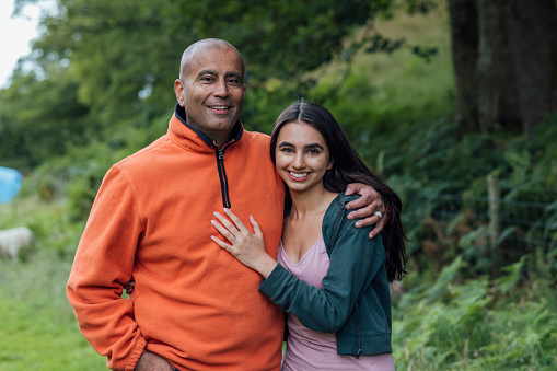 A close up of a father and his teenage daughter who are enjoying a family trip to the Lake District in Keswick in Cumbria. They are smiling at the camera with their arm around each other.