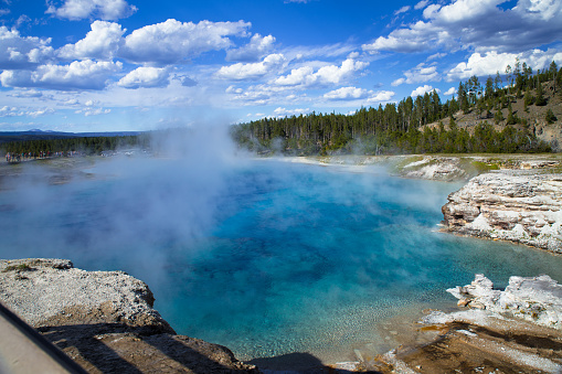 the blue hot spring with steam rising from water  in Yellowstone National Park