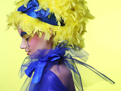 Young woman with yellow wig feather. Holiday theme.
