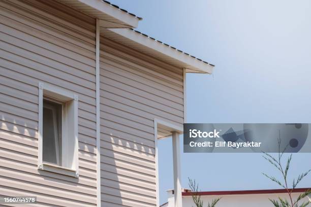 The Facade Of The New House Clad With Siding With Windows Against The Blue Sky Stock Photo - Download Image Now