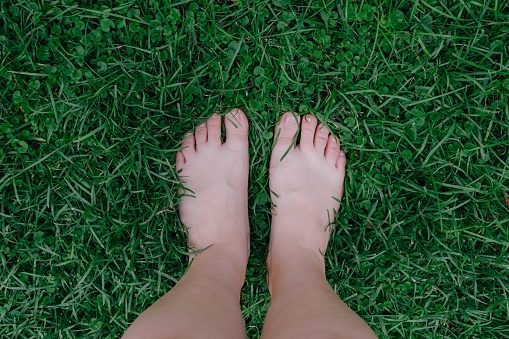 Bare woman's feet on the green grass, happy and peaceful