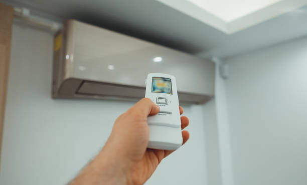istock Hand holding remote control in front of the air conditioner. 1560745265