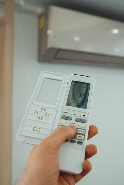 istock Hand holding remote control in front of the air conditioner. 1560745267
