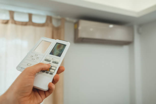 istock Hand holding remote control in front of the air conditioner. 1560745268