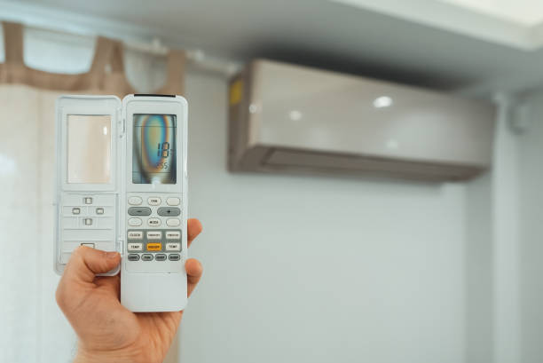 istock Hand holding remote control in front of the air conditioner. 1560745270