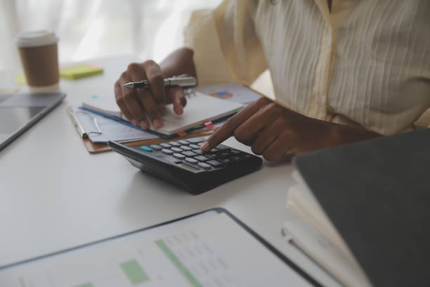 istock Asian Businesswoman Using laptop computer and working at office with calculator document on desk, doing planning analyzing the financial report, business plan investment, finance analysis concept. 1560833497