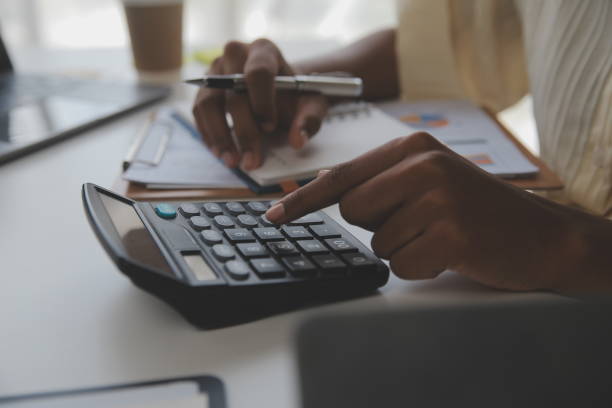 istock Asian Businesswoman Using laptop computer and working at office with calculator document on desk, doing planning analyzing the financial report, business plan investment, finance analysis concept. 1560833547