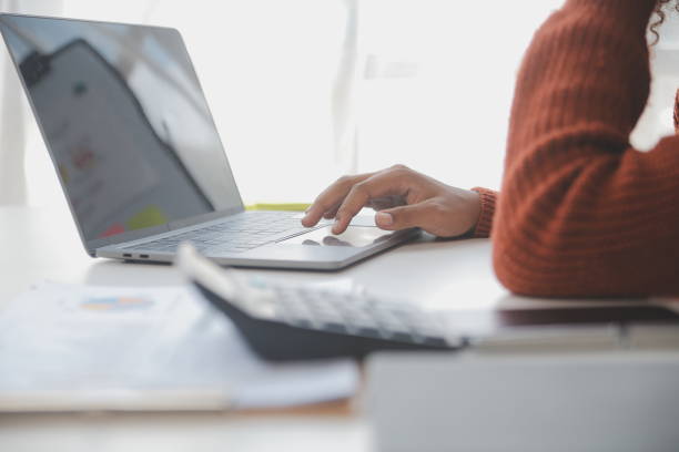 istock Asian Businesswoman Using laptop computer and working at office with calculator document on desk, doing planning analyzing the financial report, business plan investment, finance analysis concept. 1560836097