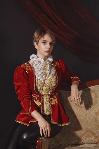 A woman in a red vintage jacket embroidered with gold patterns. Vintage portrait of a young lady in a red ballet costume in the Baroque style.