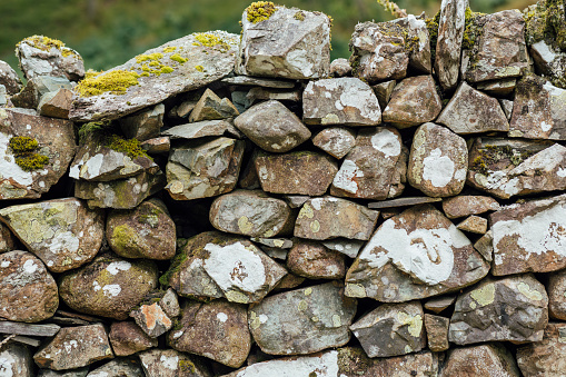 A close up of a traditional stone wall in the Lake District in Cumbria. The stone wall uses traditional methods to create an intricate strong wall that is used to line fields and agricultural fields.