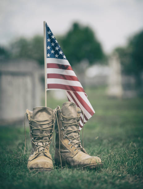 Old military combat boots against American flag stock photo