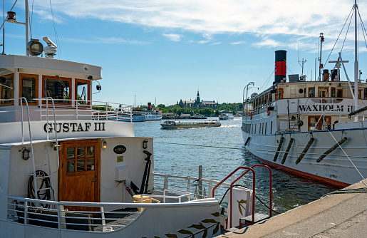 traditional white cruising ships at the quai in the harbour of Stockholm with the nordic museum in the background, Sweden