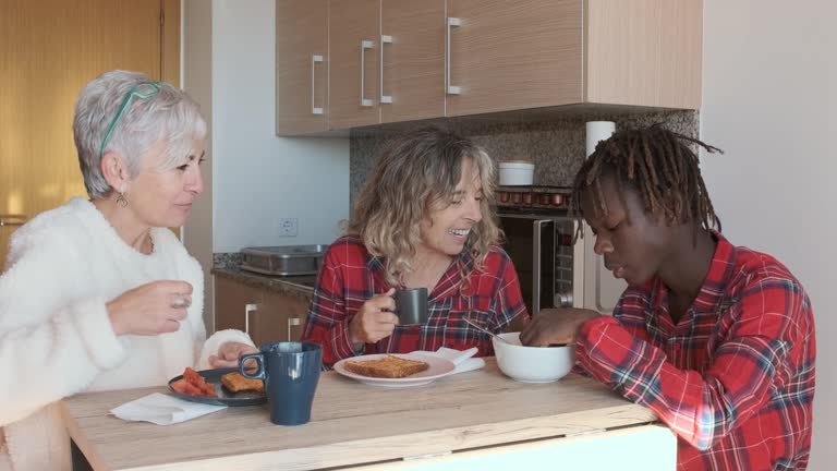 Mature lesbian couple enjoying having breakfast with their son at home.