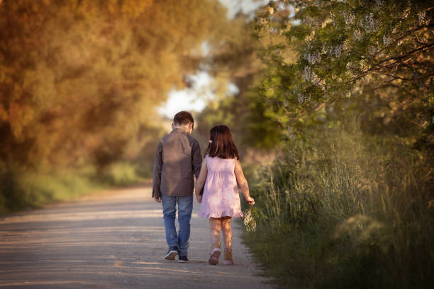 istock Little siblings walking away hand in hand 1560925491