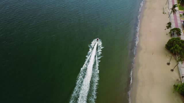 drone point of view of a jet ski sailing on the beach
