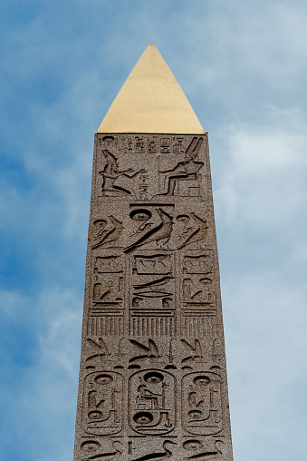 Point detail of the Obelisk of Luxor in Place de la Concorde. The Place de la Concorde (French: 'Concord Square') is one of the major public squares in Paris, France. \nThe centrepiece of the place is an ancient Egyptian obelisk decorated with hieroglyphics exalting the reign of the pharaoh Ramesses II. It is one of two which the Egyptian government gave to the French in the 19th century. The other one stayed in Egypt, too difficult and heavy to move to France with the technology at that time. On September 26, 1981, President François Mitterrand formally returned the title of the second obelisk to Egypt. The obelisk once marked the entrance to the Luxor Temple.