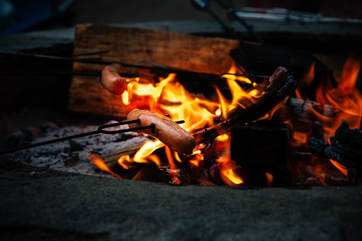 A Hotdog roasting over a camp fire