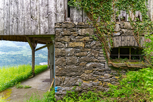 Scenic landscape with stone and wooden wall of barn at Swiss path hiking trail at village of Seelisberg on a cloudy spring day. Photo taken May 18th, 2023, Seelisberg, Switzerland.