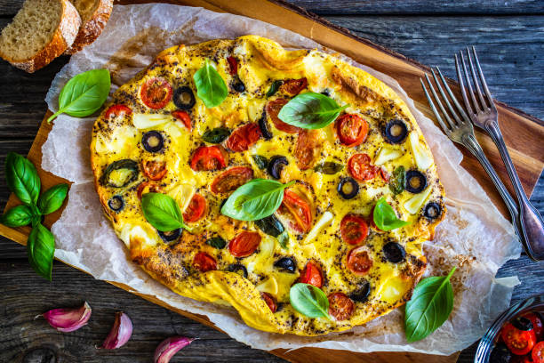 Frittata - scrambled eggs with mozzarella and vegetables on wooden table