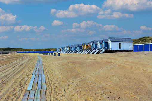 Vlissingen - beautiful sandy beach with colorful houses in a row. In the middle of the path of wooden planks. Sunny, quiet, relaxing place in the bay.