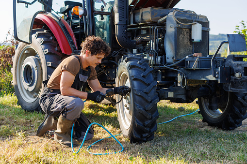 A farmer inflates a tire with a tire inflation gun