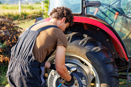 A farmer inflates a tire with a tire inflation gun
