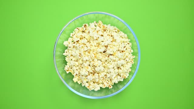 Popcorn in glass bowl. Bowl of salty and sweet popcorn on green background.