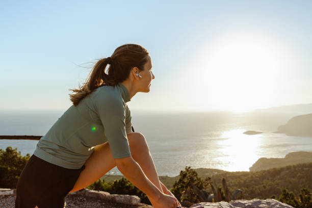 istock Young woman tying shoelaces while looking at the sea 1561084818