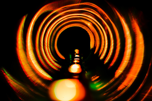 Abstract point of view created with craft materials and lighting equipment. Orange light and a spiral concentric shape formed by light strip and tube