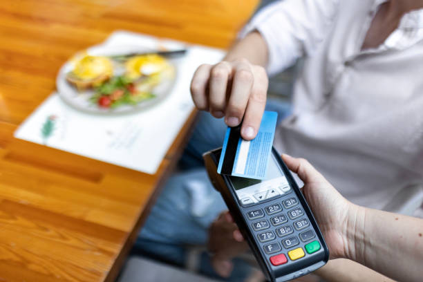 istock Smiling Unrecognizable Young Man Pays with Contactless Card at Restaurant 1561220979