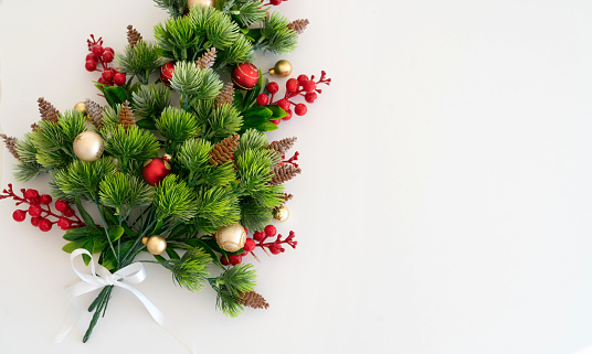 Christmas banner with green fir tree branches, mistletoe and red baubles decoration on white background. The composition is at the left of an horizontal frame leaving useful copy space for text and/or logo.