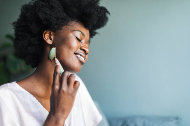istock Young adult black woman using gua sha for face massage 1561229257