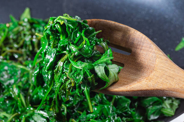 istock Wilted arugula or rocket salad, preparing a side dish to steak, in frying pan, horizontal closeup 1561285320